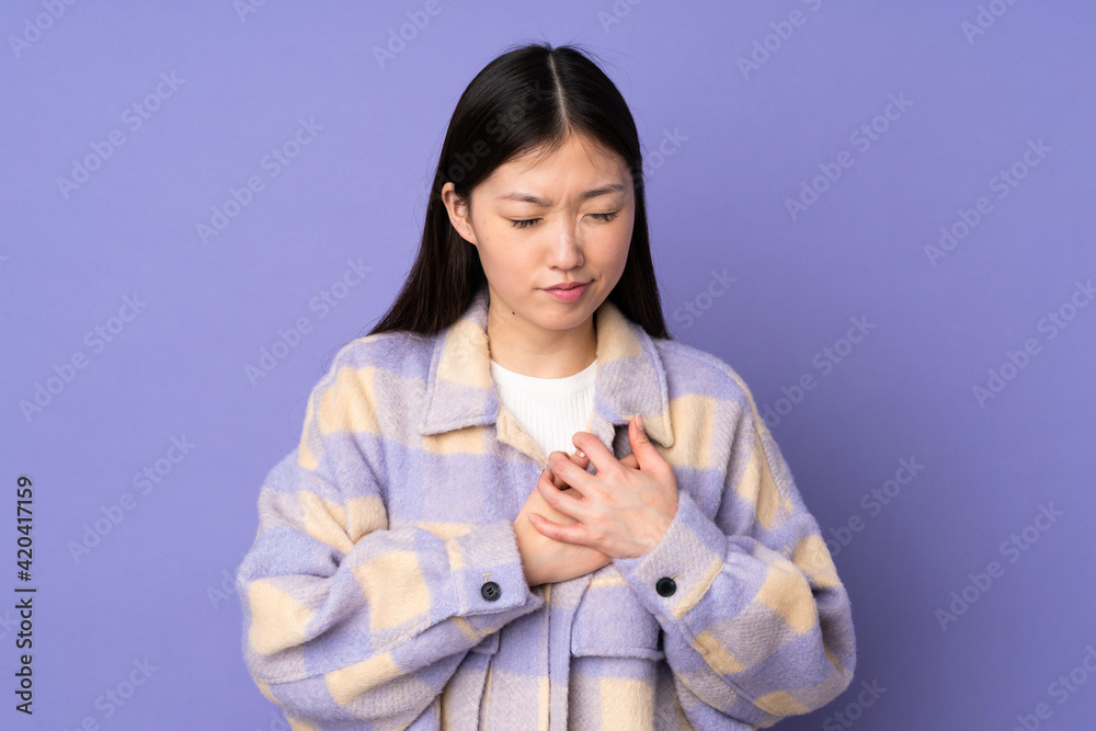 Young asian woman isolated on purple background having a pain in the heart Young asian woman isolated on purple background having a pain in the heart