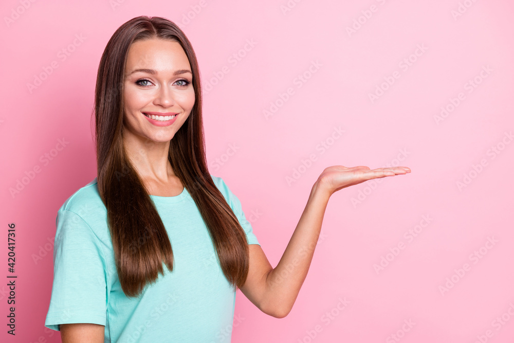 Photo portrait of smiling woman keeping blank space on hand isolated on pastel pink color background Photo portrait of smiling woman keeping blank space on hand isolated on pastel pink color background