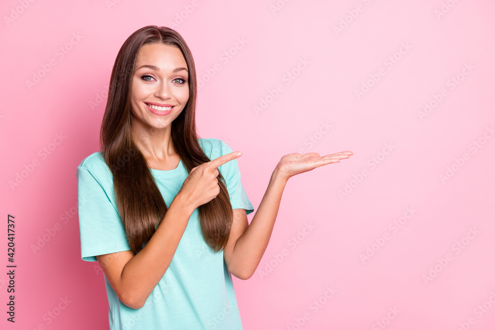Photo portrait of cheerful girl holding empty space on hand pointing finger smiling isolated on pastel pink color background Photo portrait of cheerful girl holding empty space on hand pointing finger smiling isolated on pastel pink color background