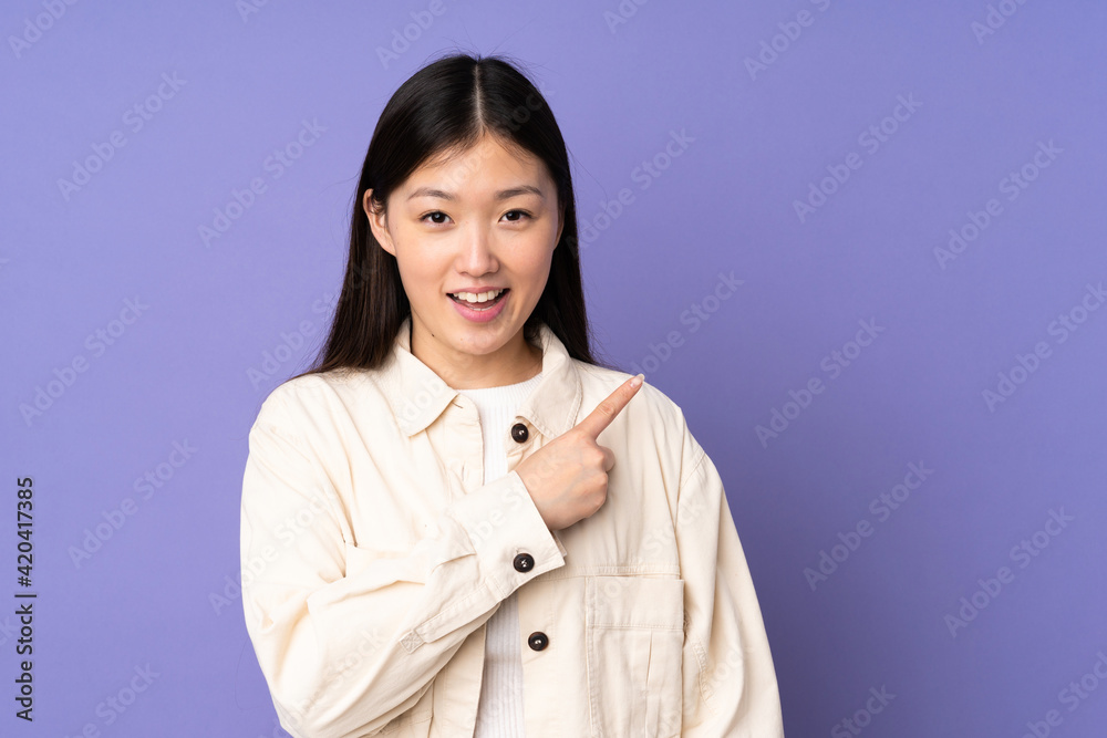 Young asian woman isolated on purple background pointing to the side to present a product Young asian woman isolated on purple background pointing to the side to present a product