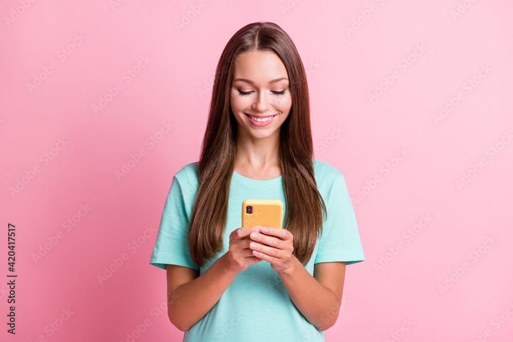 Photo portrait of smiling woman keeping smartphone using app smiling isolated on pastel pink color background Photo portrait of smiling woman keeping smartphone using app smiling isolated on pastel pink color background