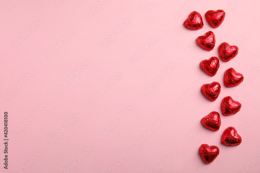 Heart shaped chocolate candies on pink background, flat lay with space for text. Valentine's day treat