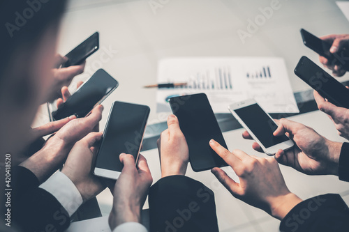 group of employees using their smartphones in the workplace