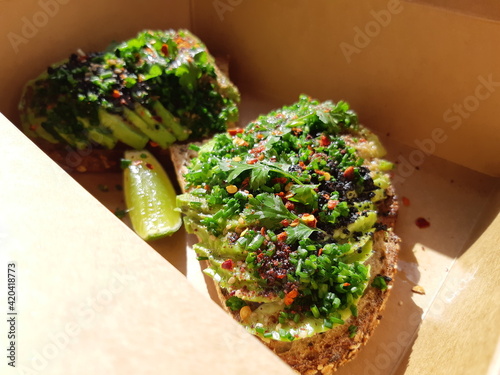 Canvas Print Vegan toast bread with avocado and vegetable toppings in take away lunchbox