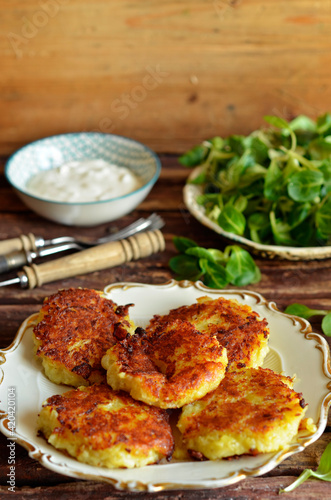Rosti, potato pancakes served on a rustic cream-colored plate on a wooden background