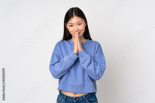Young asian woman isolated on background keeps palm together. Person asks for something