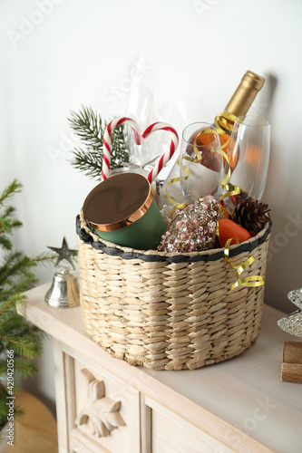 Wicker basket with gift set and Christmas decor on shelf