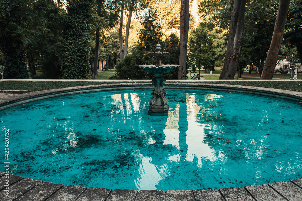 Decorated fountain and artificial pond with blue water in park