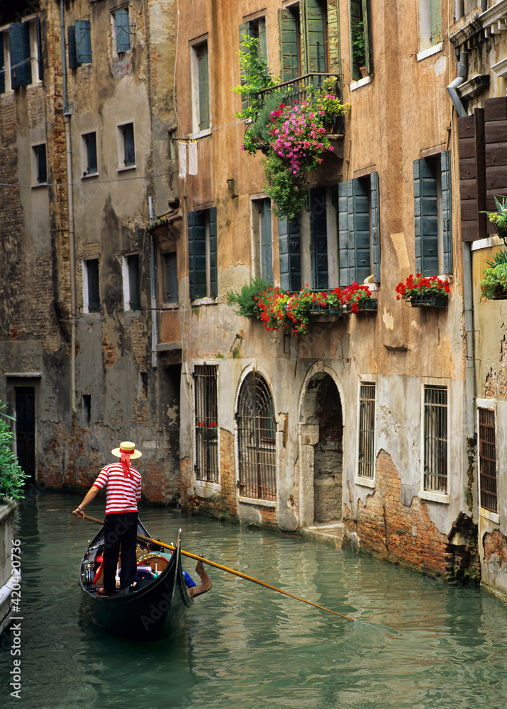 Gondola and Gondolier and flower-filled window boxes on side canal in Venice