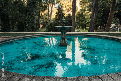 Decorated fountain and artificial pond with blue water in park