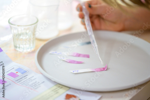 A girl plays with a children's chemical kit. Word Vinegar on the litmus paper.