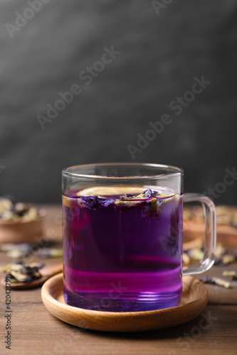 Glass mug of organic blue Anchan on wooden table, space for text. Herbal tea