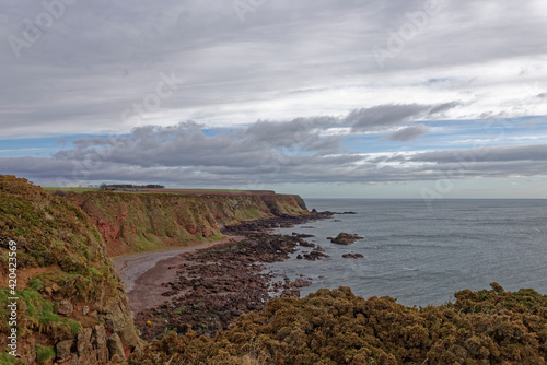 Looking north from Rumness Bay along the steep sandstone grass covered Cliffs and inaccessible shingle beaches of the East Coast of Scotland.