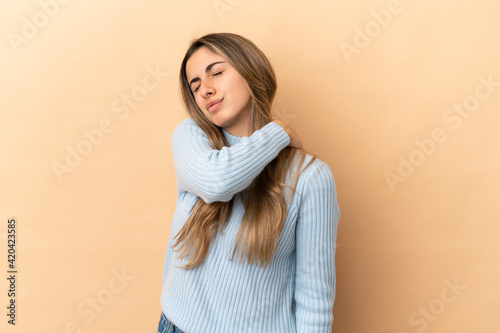 Young caucasian woman isolated on beige background suffering from pain in shoulder for having made an effort