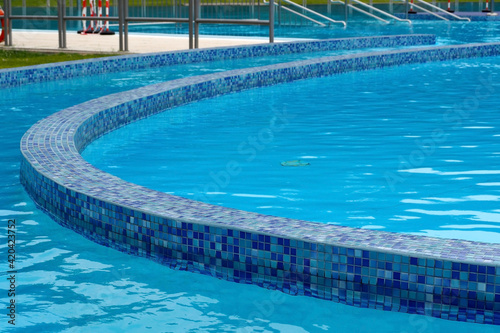 blue clear water in an outdoor pool tiled with mosaics side view