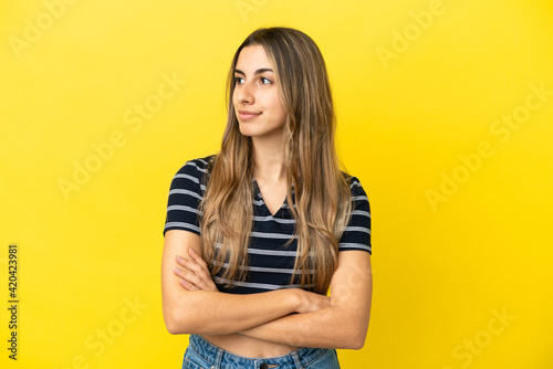 Young caucasian woman isolated on yellow background looking to the side © luismolinero