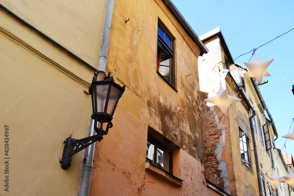 Fototapeta premium Narrow pedestrian street with star shaped lanterns hanging above. Old Town of Riga, Latvia, Baltic States