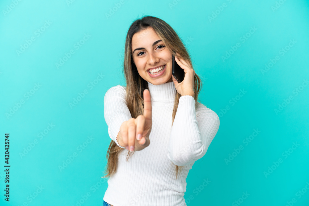 Young caucasian woman using mobile phone isolated on blue background showing and lifting a finger Young caucasian woman using mobile phone isolated on blue background showing and lifting a finger