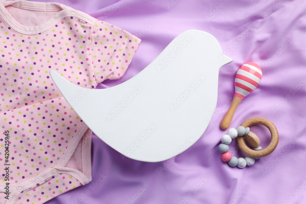 Flat lay composition with bird shaped child's night lamp on violet fabric