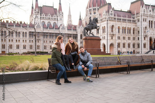 Travel to Hungary, European tour. Tourists - Girls and a guy near the Hungarian parliament. A group of people are traveling across Europe.