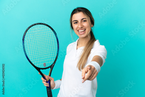 Young caucasian woman isolated on blue background playing tennis and pointing to the front