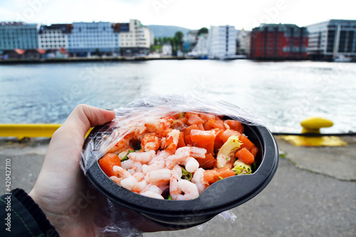 Seafood plate on the background of the buildings and the bay in Bergen, Norway, Scandinavia. Sea salad close-up.