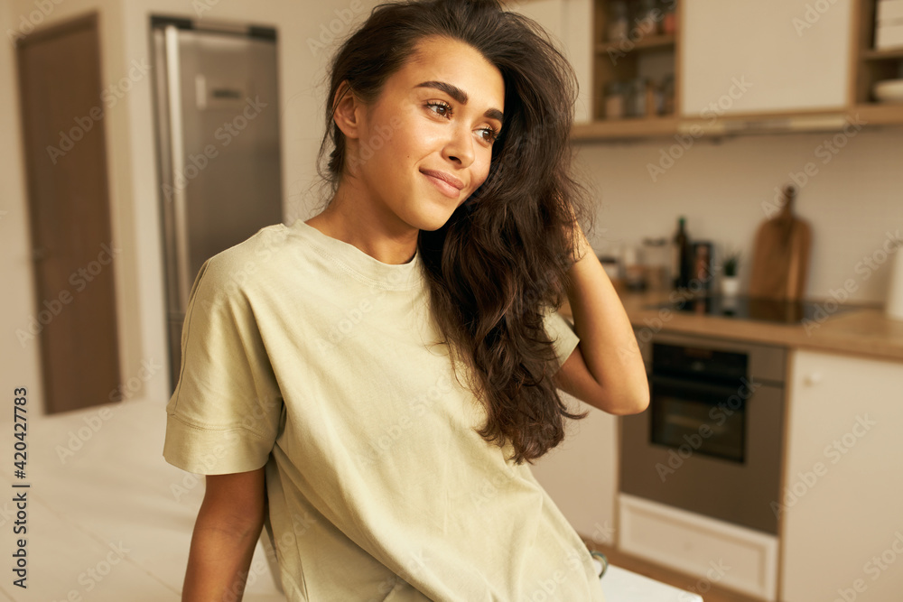 Horizontal shot of beautiful slender young mixed race female in casual clothing having dreamy pensive look, thinking about something pleasant. Home, domesticity, coziness and lifestyle concept Horizontal shot of beautiful slender young mixed race female in casual clothing having dreamy pensive look, thinking about something pleasant. Home, domesticity, coziness and lifestyle concept