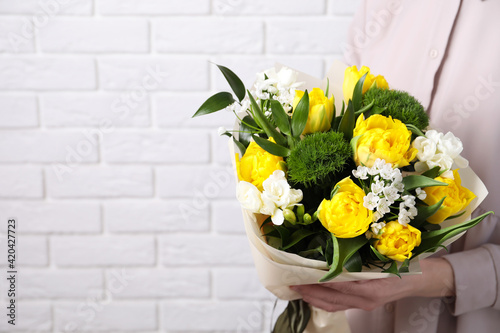Woman with bouquet of beautiful tulips near white brick wall, closeup. Space for text