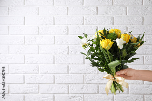 Woman with bouquet of beautiful peony tulips near white brick wall, closeup. Space for text