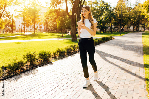 Image of woman's hand holding mobile phone outdoors