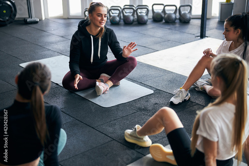 Tablou pe pânză Dedicated female coach lecturing young athletic women