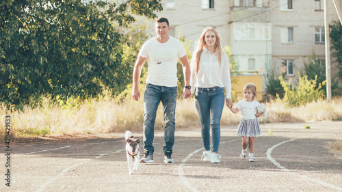 a family with a little daughter and a fox terrier walking in the city on the road