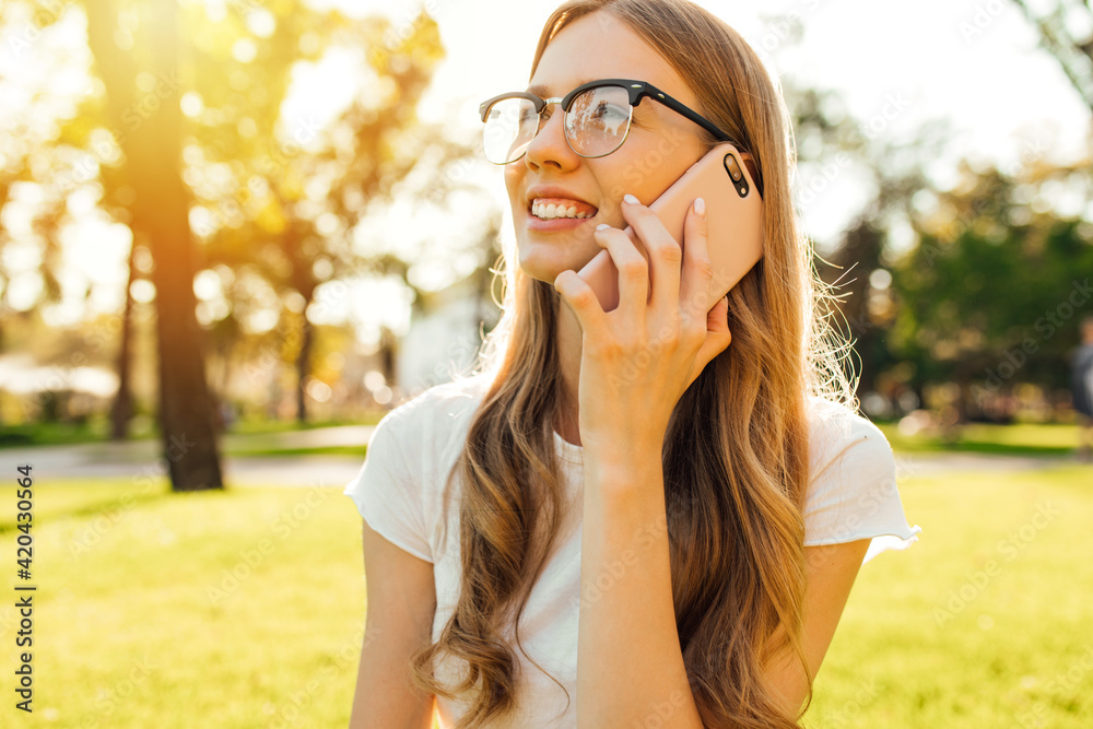 Young woman talking on the phone while sitting in the park on a green lawn Young woman talking on the phone while sitting in the park on a green lawn