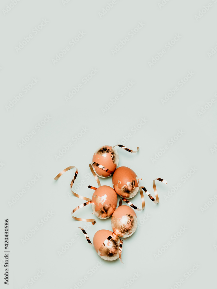 Fototapeta premium Holiday Easter golden and bronze eggs on blue background. Spring greeting card. Flat lay, top view.