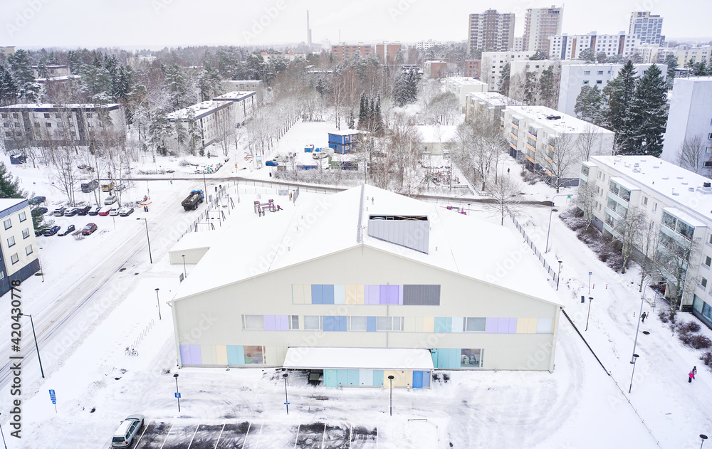 Aerial view of Matinkyla neighborhood of Espoo, Finland. Snow-covered city in winter. On the foreground modern building of the kindergarten.
