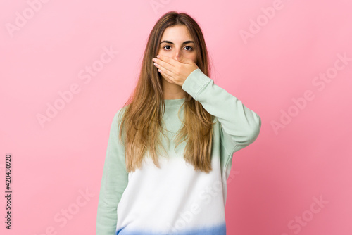Young woman over isolated pink background covering mouth with hand