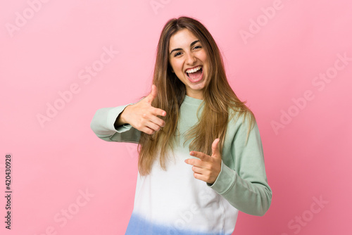 Young woman over isolated pink background pointing to the front and smiling