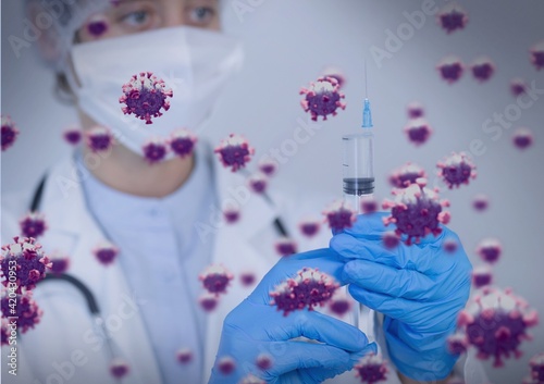 Composition of covid 19 cells and biohazard symbol over male doctor holding syringe