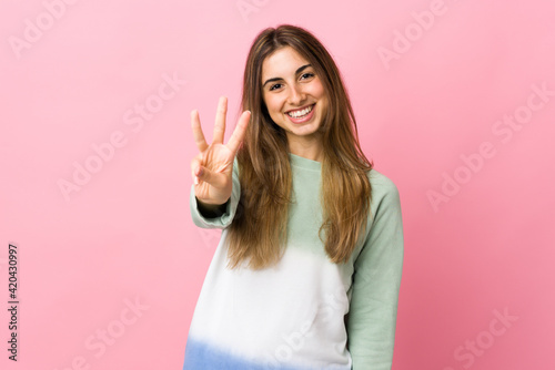 Young woman over isolated pink background happy and counting three with fingers © luismolinero