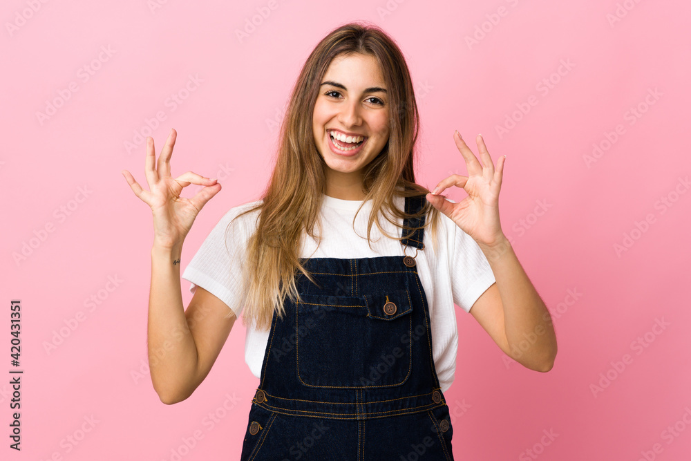 Young woman over isolated pink background showing ok sign with two hands Young woman over isolated pink background showing ok sign with two hands