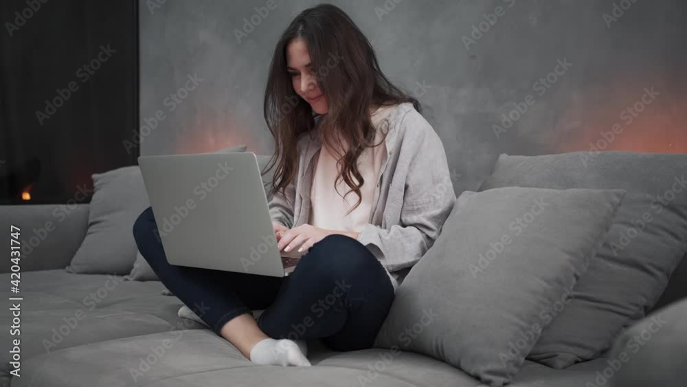 A beautiful woman is using her laptop sitting in the living room at home A beautiful woman is using her laptop sitting in the living room at home