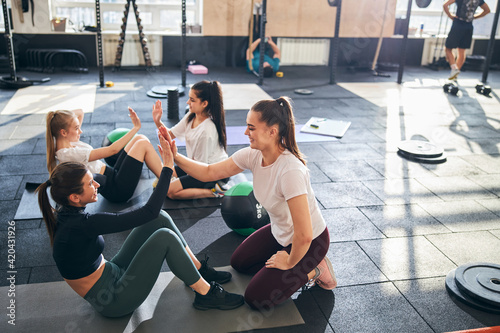 Fototapeta Naklejka Na Ścianę i Meble -  Positive ladies doing abs workout at the gym