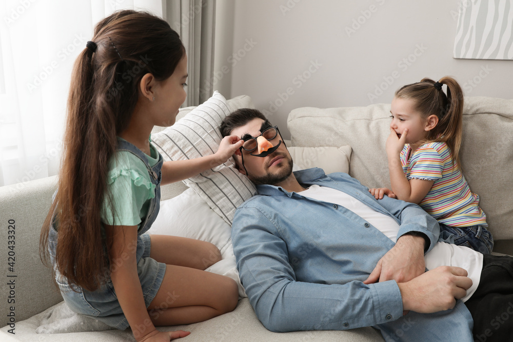 Cute little children putting funny glasses on father while he sleeping at home Cute little children putting funny glasses on father while he sleeping at home