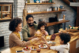 Happy black family toasting with drinks at dining table.