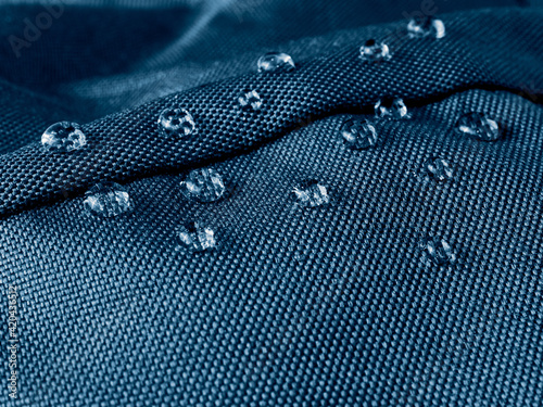 Water drops on waterproof membrane fabric. Detail view of texture of blue waterproof cloth.