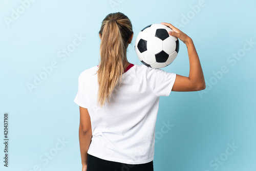 Young hispanic woman over isolated blue background with soccer ball