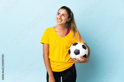 Young hispanic football player woman over isolated on blue background thinking an idea while looking up © luismolinero