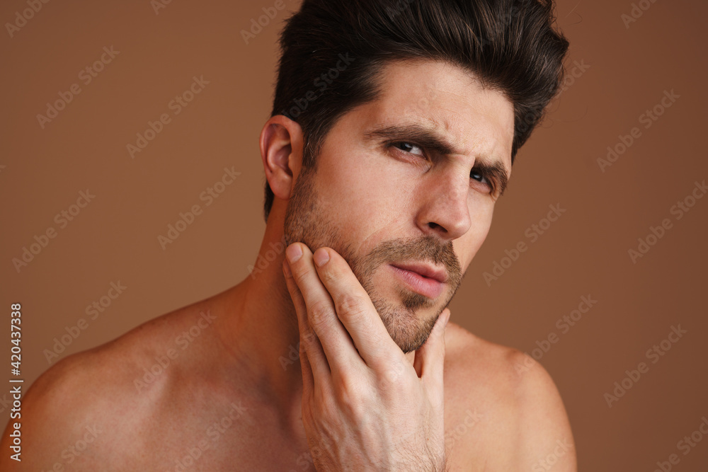 Obraz premium Brooding half-naked man looking at camera and rubbing his face