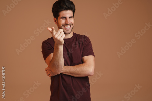 Joyful masculine man smiling and pointing finger at camera