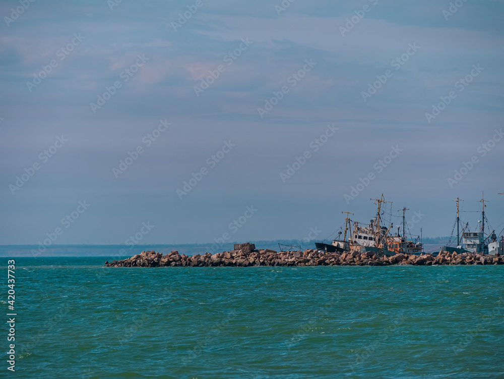 Empty beach with blue sea and sky background on a sunny day. South scenic marine landscape wallpaper, autumn winter sping summer vacation season. Deserted seaport on the shore with cranes and boats.